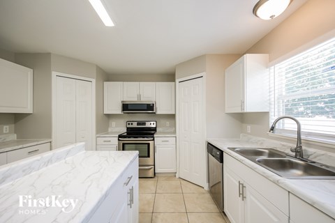 A kitchen with white cabinets and a marble countertop.