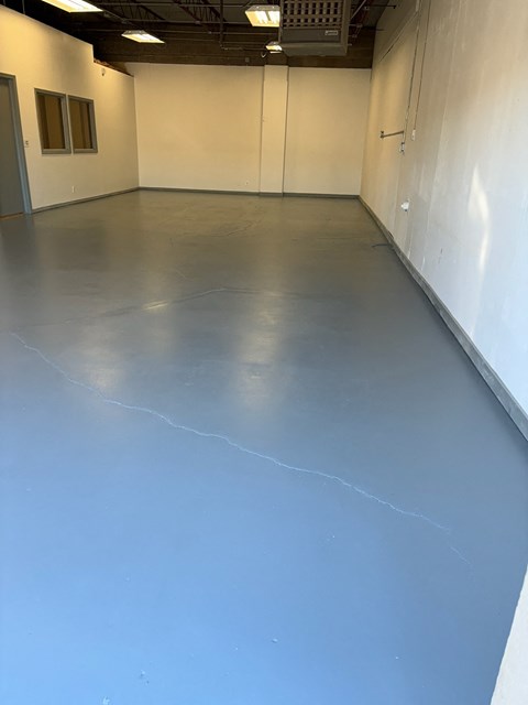 A large empty room with a grey floor and white walls.