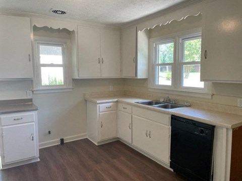 A kitchen with white cabinets and a black dishwasher.