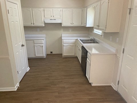 A kitchen with white cabinets and a wooden floor.