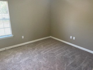 A room with a carpeted floor and a window.