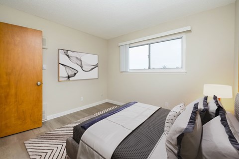 A bedroom with a bed, a rug, and a painting on the wall.