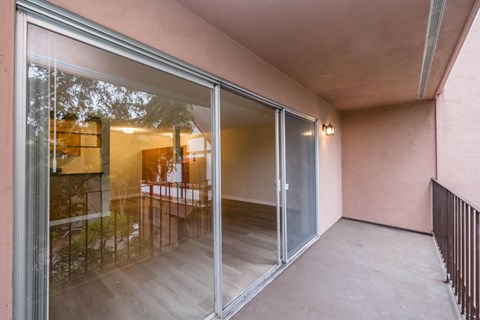 A balcony with glass doors leading to a room with a pink wall.