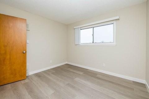 A room with a wooden door and a window with a white frame.