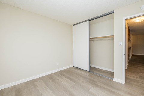 A room with a white wall and a white closet with a shelf.