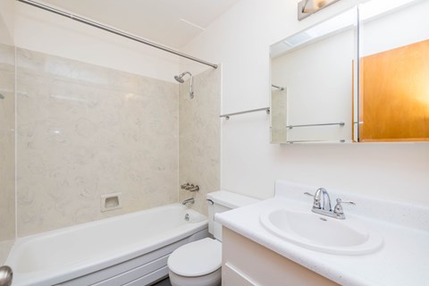 A white bathroom with a toilet, sink, and bathtub.