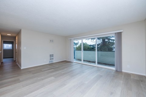 A room with a sliding glass door leading to a balcony.