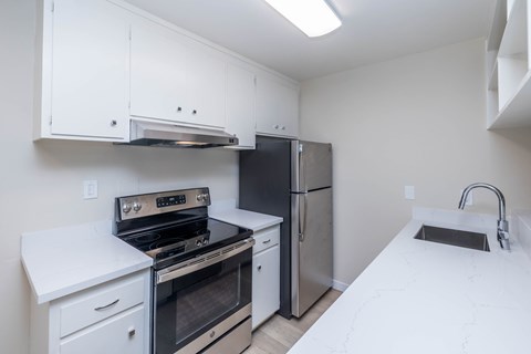 A kitchen with a stove, refrigerator, and sink.
