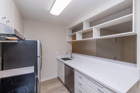 A kitchen with a black fridge and white countertops.