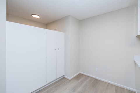 A room with white walls and a wooden floor with a white cabinet.