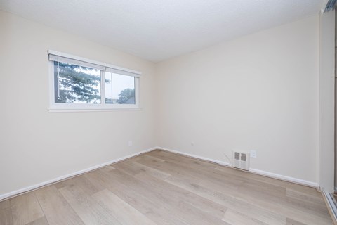 A room with a window and wooden flooring.