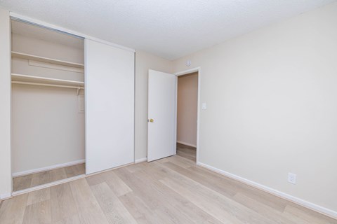 A room with a white door and a white closet with shelves.