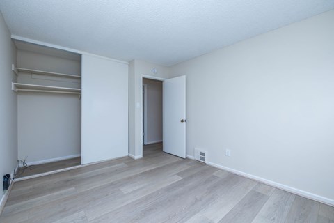 A room with a door and a closet with shelves.