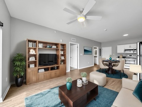 A modern living room with a ceiling fan and a blue rug on the floor.