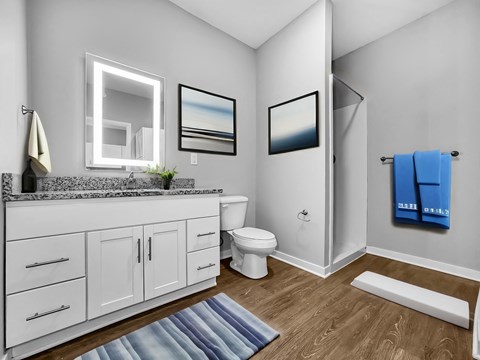 A bathroom with a white toilet, a sink with a mirror above it, and a blue towel hanging on the door.