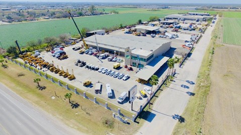an aerial view of a building with a parking lot and a field