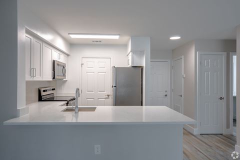 a kitchen with a white counter top and a stainless steel refrigerator