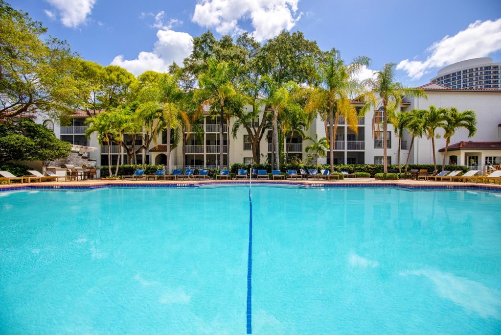 a large pool in front of a hotel with palm trees