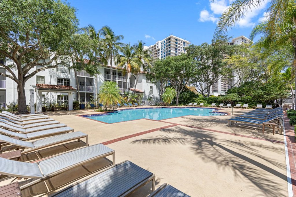 a resort style pool with lounge chairs and buildings in the background