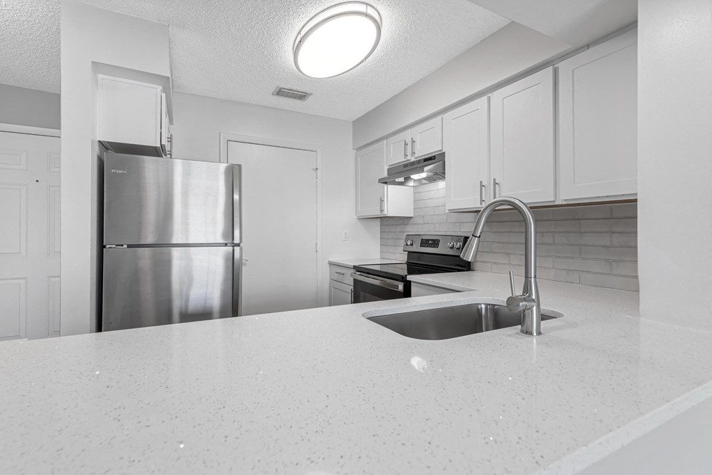 a white kitchen with stainless steel appliances and a white counter top