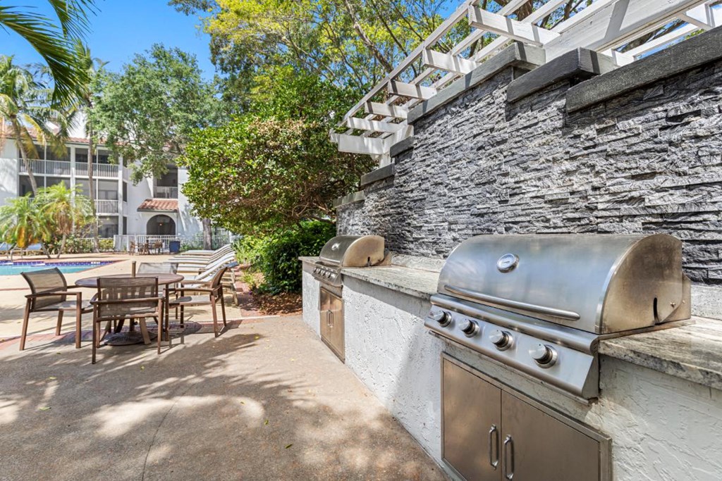 a barbecue grill on a patio next to a swimming pool