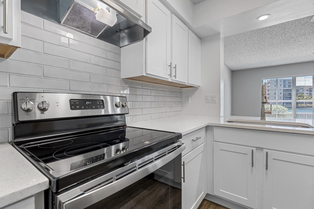 a white kitchen with a stove and a window