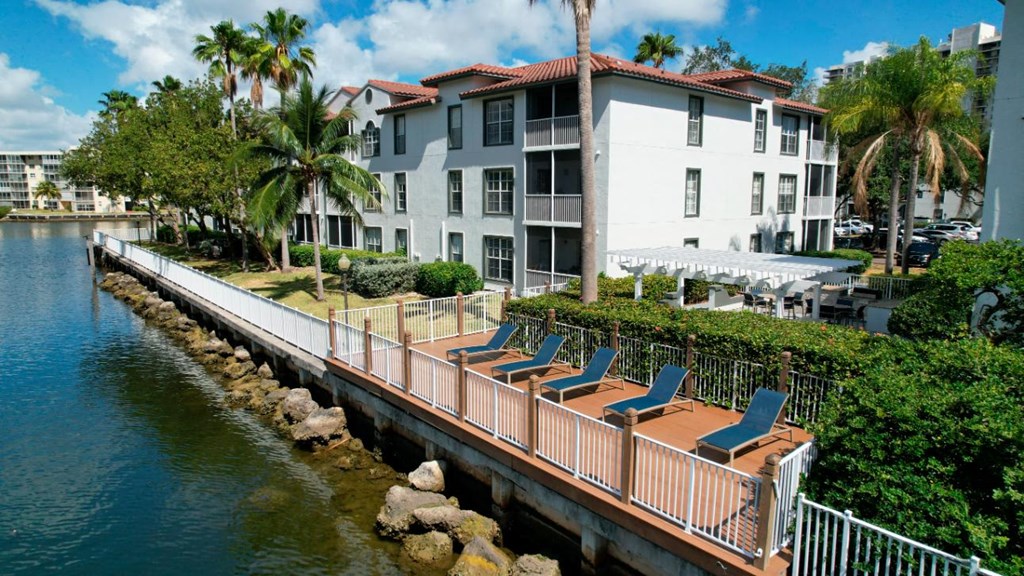 a dock with chairs overlooking the water in front of a building