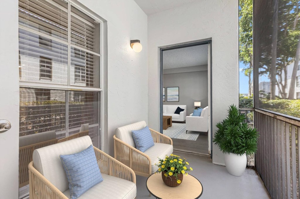 a patio with two chairs and a table and a door to a bedroom