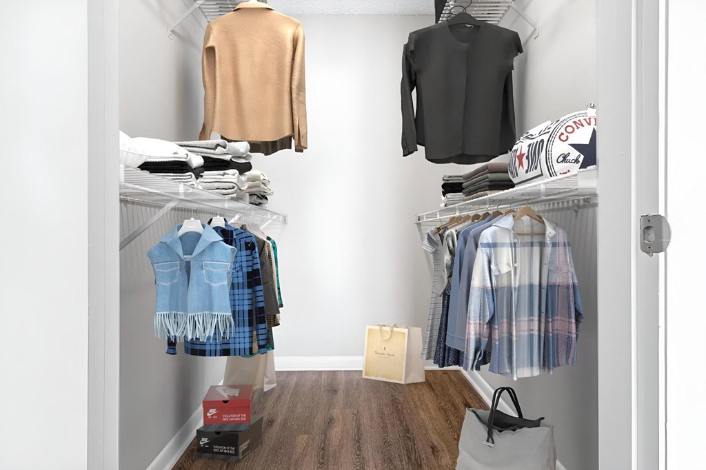 a walk in closet with clothes hanging on the wall and a closet door open