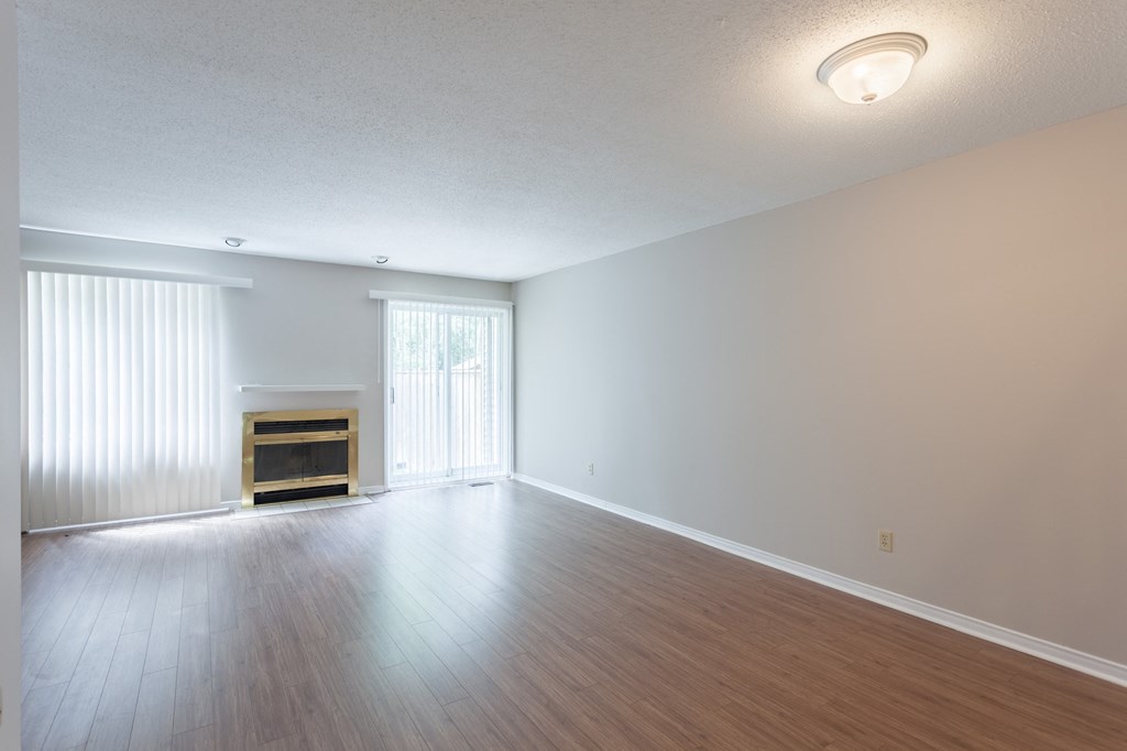 an empty living room with a fireplace and wood flooring