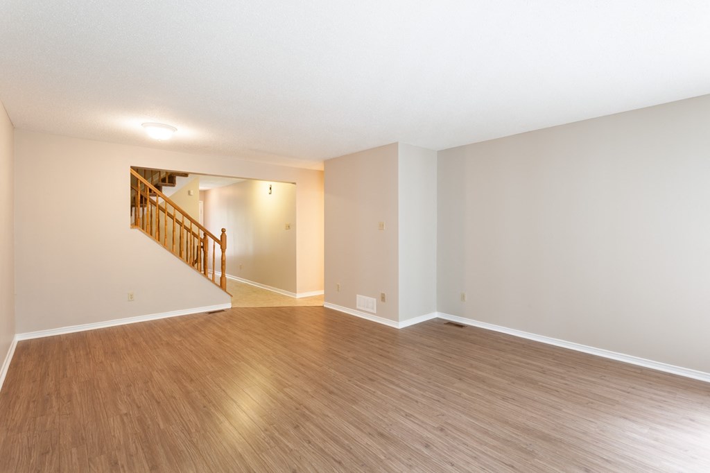 an empty living room with wood flooring and a staircase