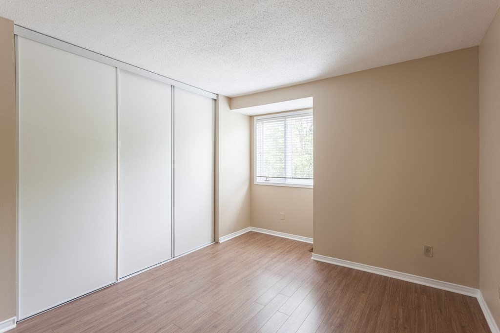 an empty room with white closet doors and a window