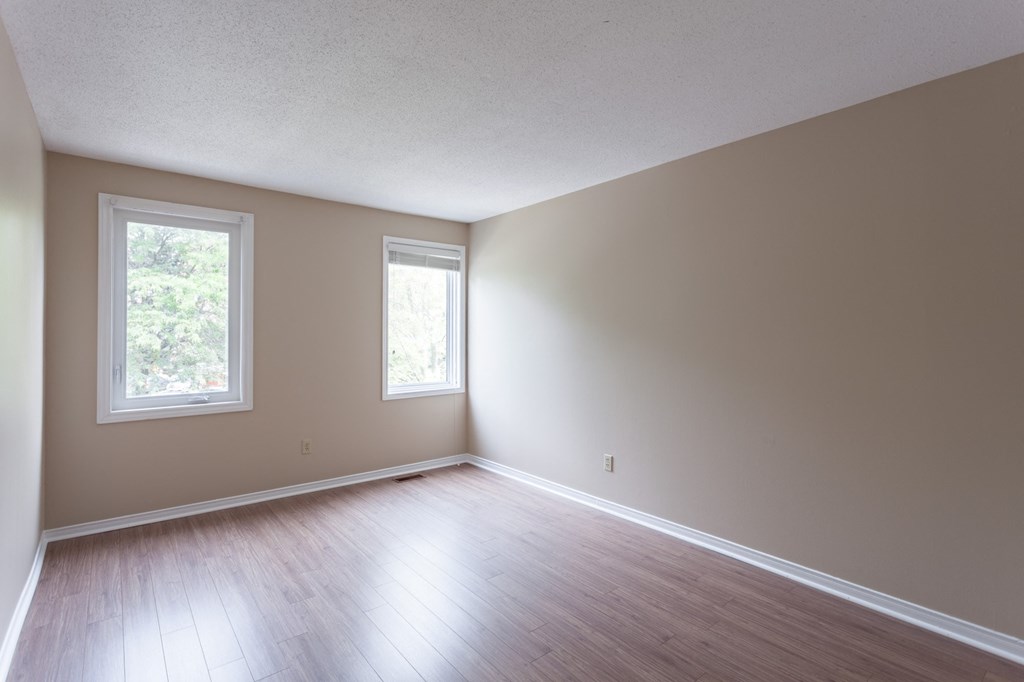 an empty living room with wood floors and two windows