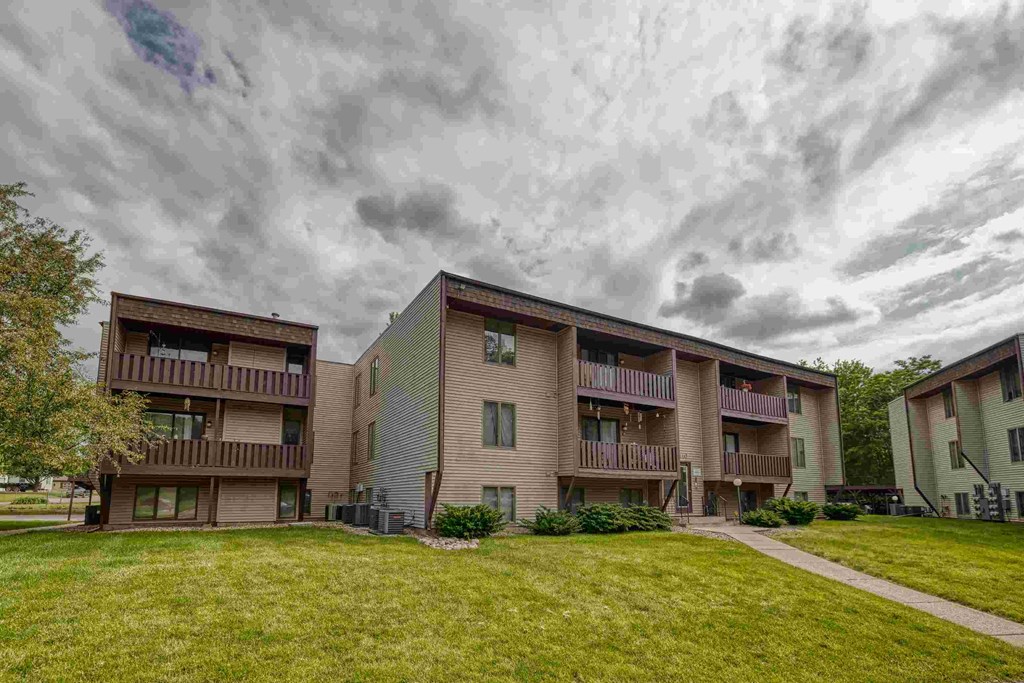 Apartment buildings with balconies and a cloudy sky above.