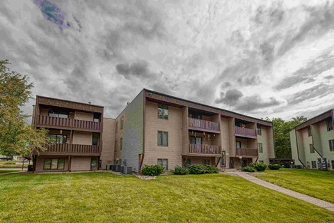 Apartment buildings with balconies and a cloudy sky above.