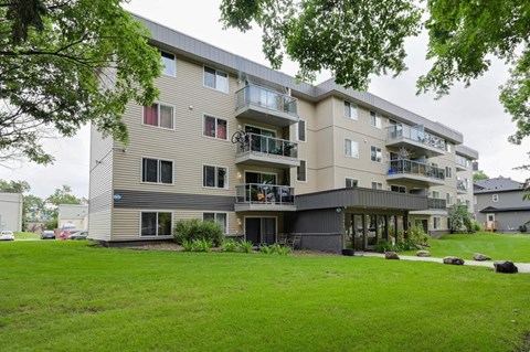 an apartment building with a green lawn in front of it