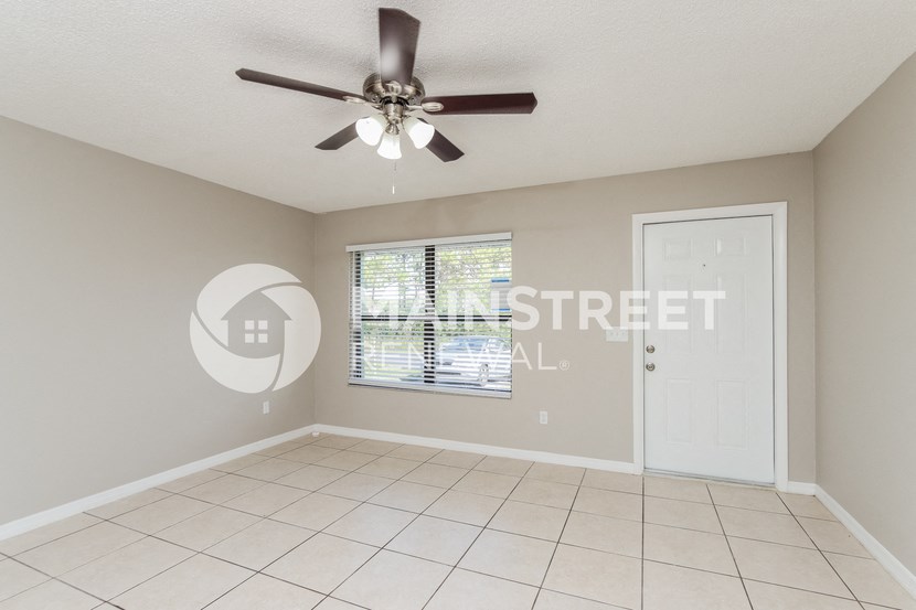 an empty living room with a ceiling fan and a window