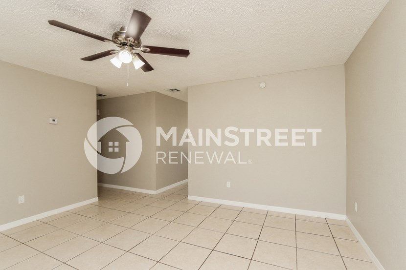 a living room with a ceiling fan and a tile floor