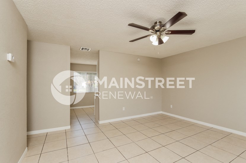 a clean and empty living room with a ceiling fan