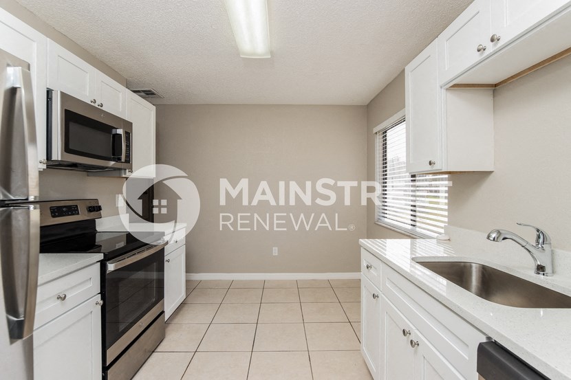 a renovated kitchen with white cabinets and black appliances and a sink