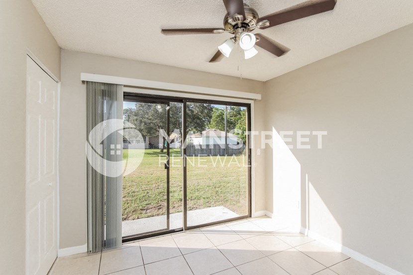 a living room with a sliding glass door and a ceiling fan