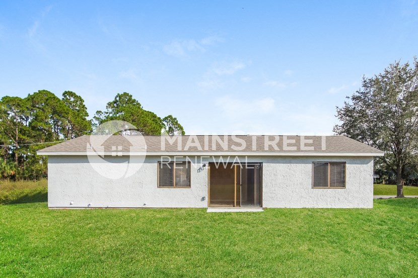 front view of a small white building with grass and trees