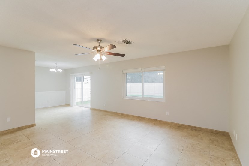an empty living room with a ceiling fan and a window