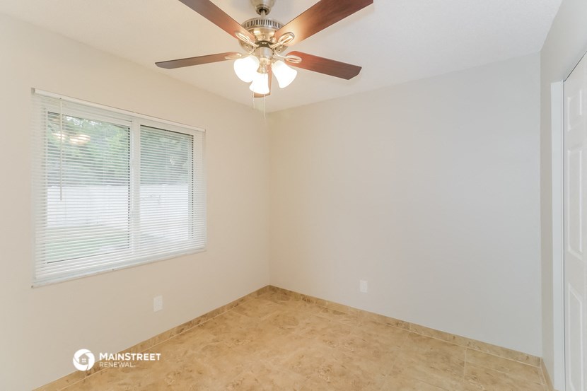 an empty bedroom with a ceiling fan and a window