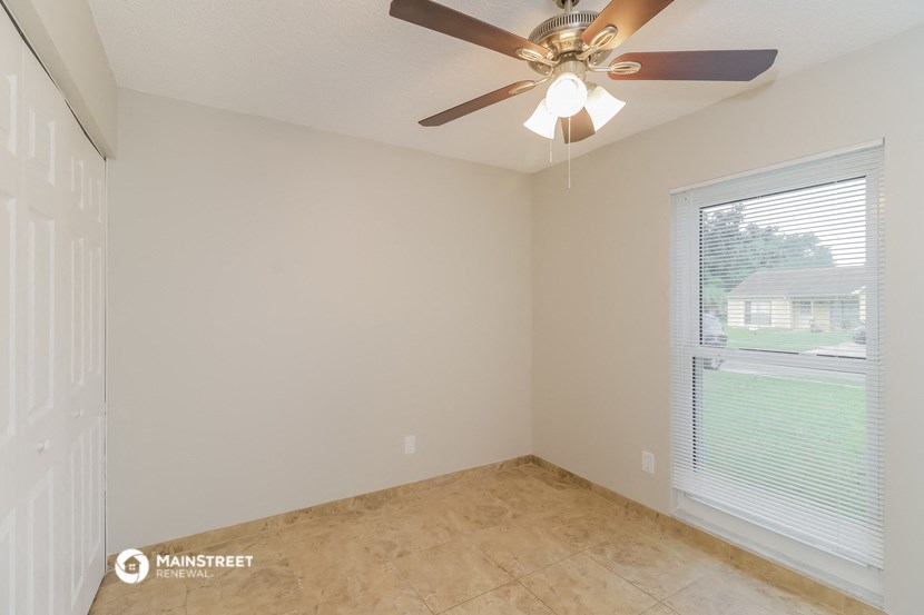 an empty bedroom with a ceiling fan and a window