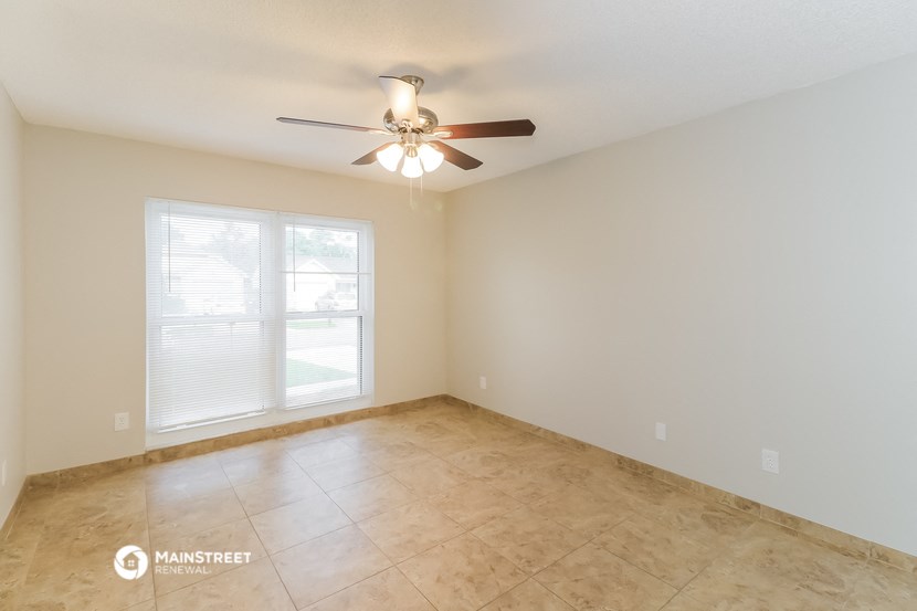 an empty living room with a ceiling fan and a window