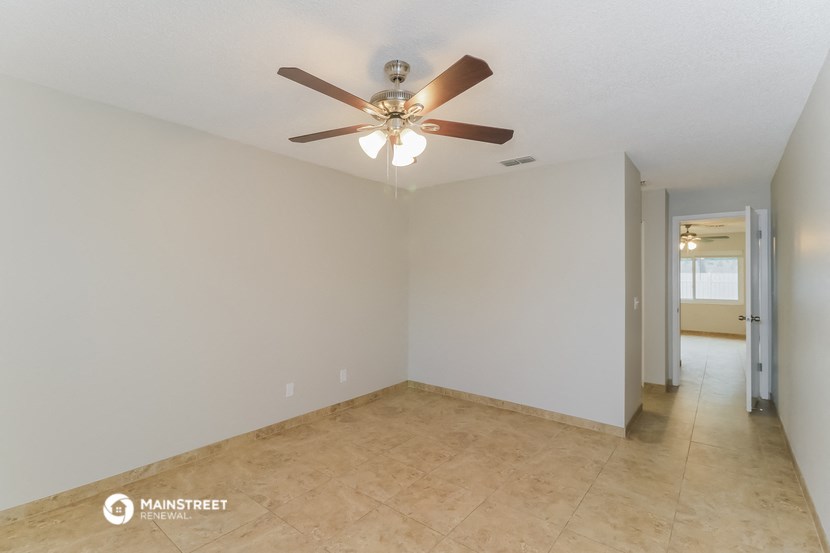 a empty living room with a ceiling fan and a tile floor