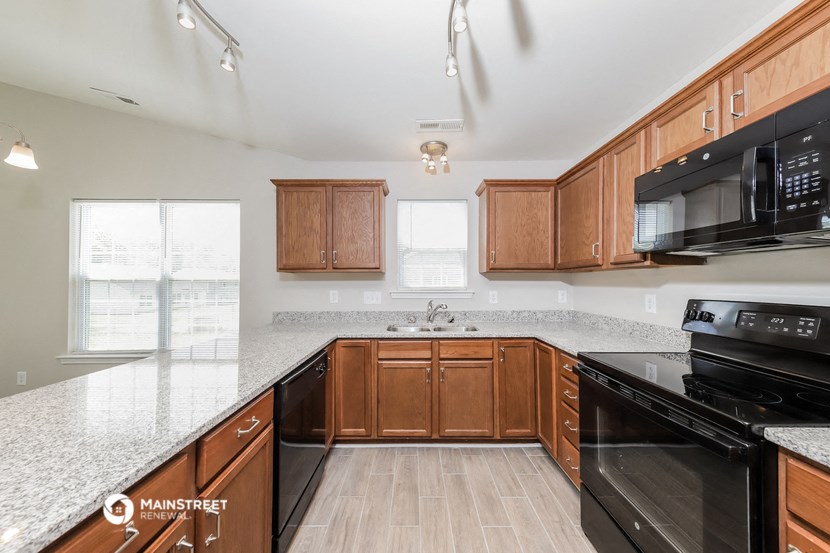a kitchen with wood cabinets and black appliances and granite counter tops