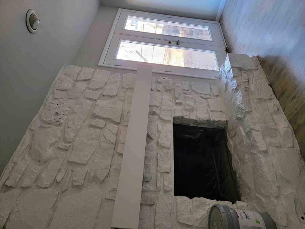 a view of a stone fireplace with a window above it