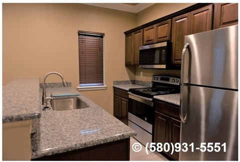 A kitchen with a stainless steel refrigerator, microwave, and oven.